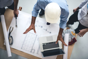 3 engineers use a laptop along with their plans to work on their project