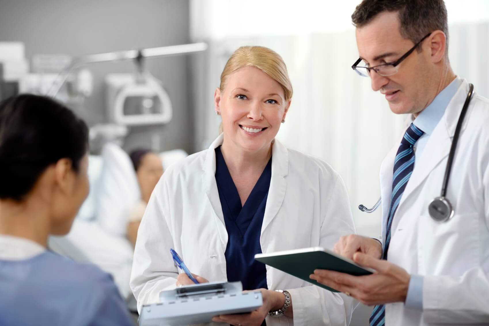 2 doctors using ipads to chart a patient’s progress 2 doctors using ipads to chart a patient's progress