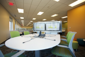 dual displays, a phone and connection cables at a huddle workspace