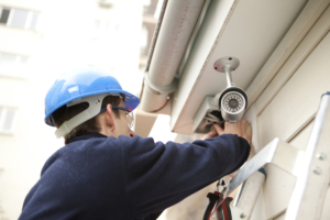 man installs security camera outside building