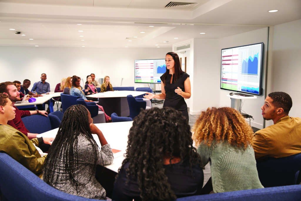 Female teacher addressing university students in a classroom woman leading a class with a tech presentation screen