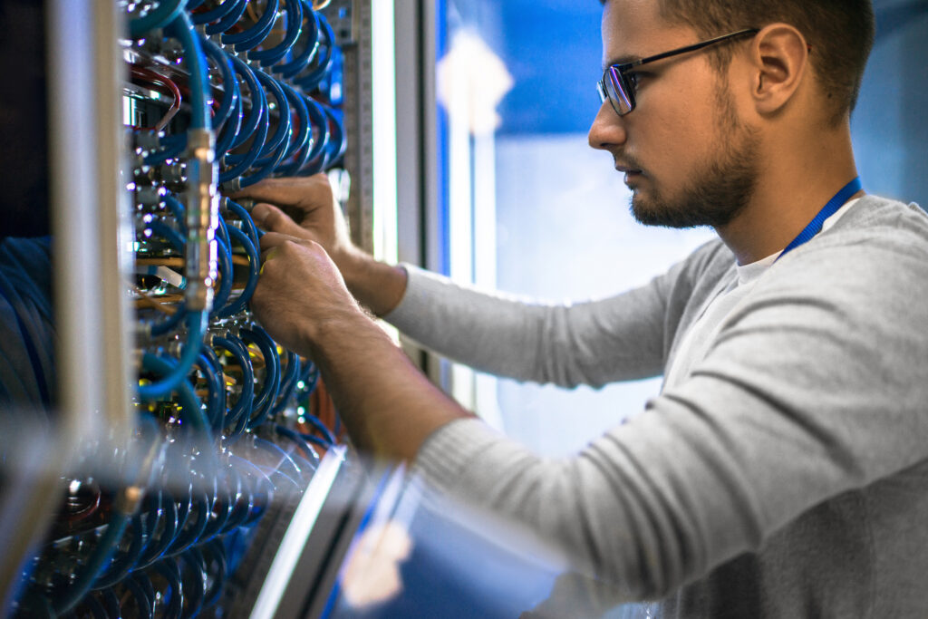 Side,View,Portrait,Of,Young,Man,Wearing,Glasses,Connecting,Cables tech with wiring and cable av rack