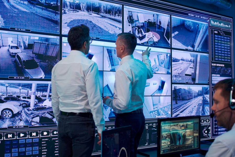 control room with lots of displays and 2 men standing in front of them